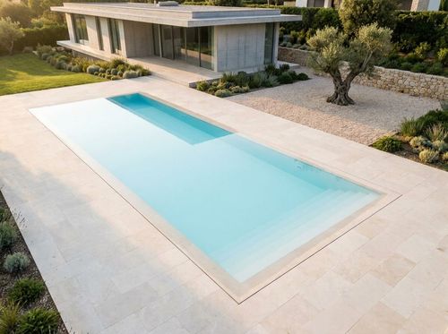 Rendering of minimalist rectangular pool set flush into a plane of pale limestone paving, very light blue water, no visible features, a single line of steps at one end, concrete-and-glass house, gravel and one sculptural tree