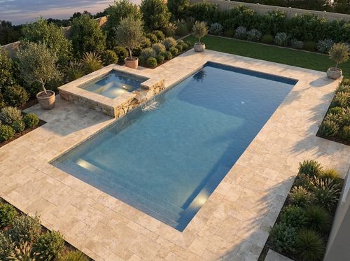 Rendering of rectangular pool with a raised attached spa spilling over a stone spillway into the pool, pebble finish with medium blue water, travertine deck, spa lit from within at dusk