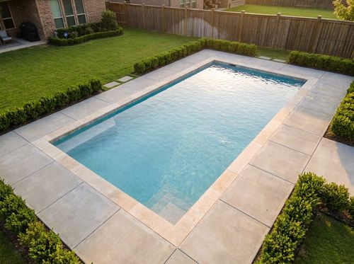 Rendering of clean rectangular in-ground pool, 16 by 32 feet, light blue quartz water, flush travertine coping, large-format concrete pavers, simple corner steps, lawn and low hedges, suburban backyard
