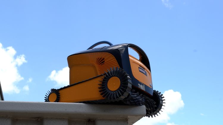 Three-quarter side view of the Dolphin Wave 90i on the pool ledge