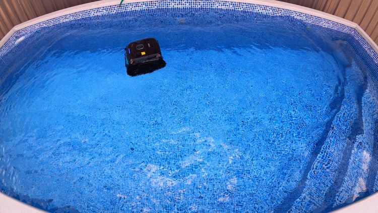The Wybot C2 floating at the pool surface between its limited cleaning cycles
