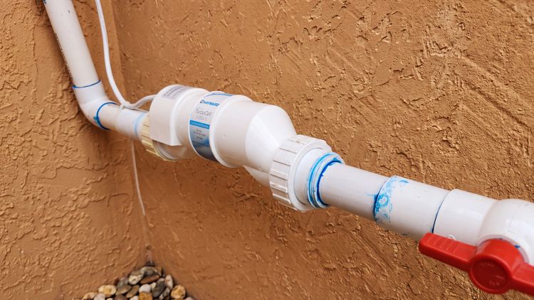 A Hayward TurboCell plumbed inline — the sealed chamber where electrolysis turns dissolved salt into chlorine
